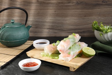 Photo of Delicious spring rolls served on black table