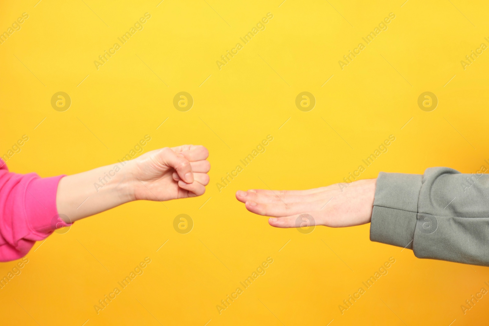 Photo of People playing rock, paper and scissors on orange background, closeup