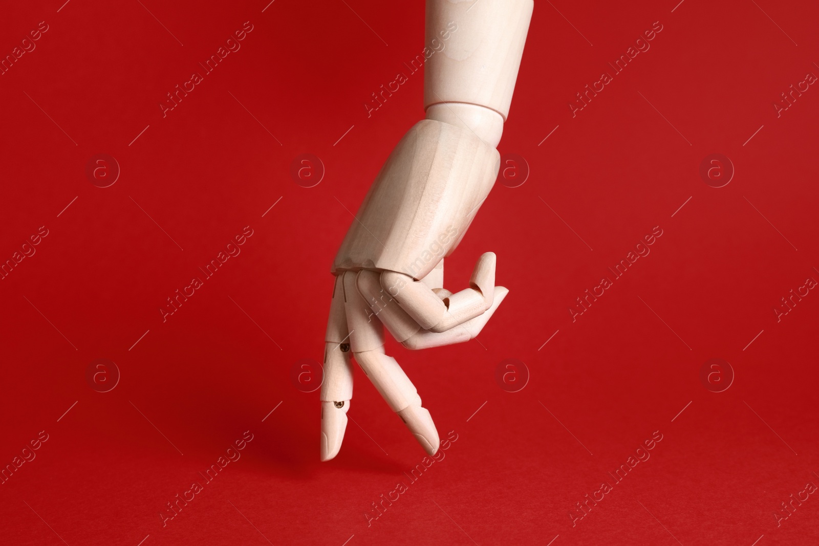 Photo of Wooden hand model on red background. Mannequin part