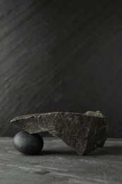 Photo of Presentation for product. Podium made of different stones on grey textured background. Space for text