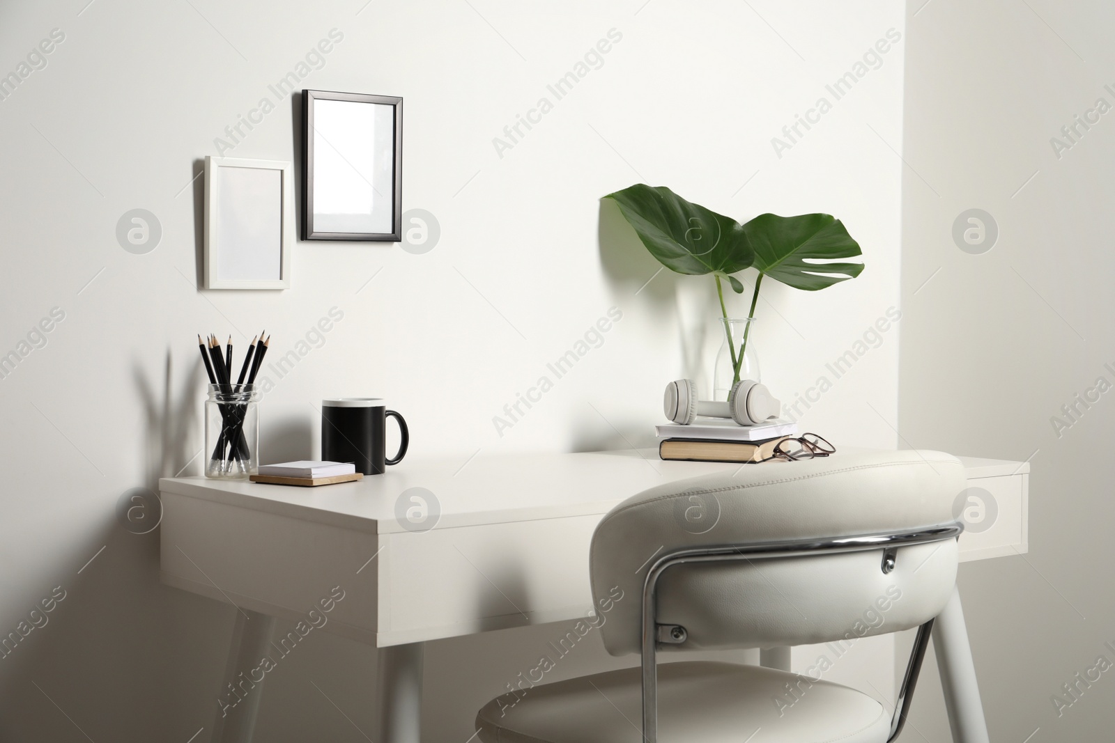 Photo of Comfortable workplace with white desk near wall at home