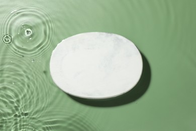 Photo of Presentation for product. Marble podium in water on green background, top view