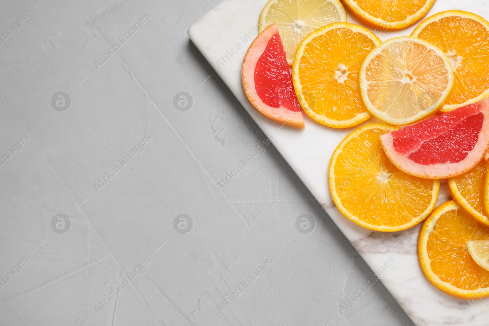 Photo of Cut citrus fruits on grey table, top view. Space for text