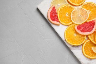 Cut citrus fruits on grey table, top view. Space for text