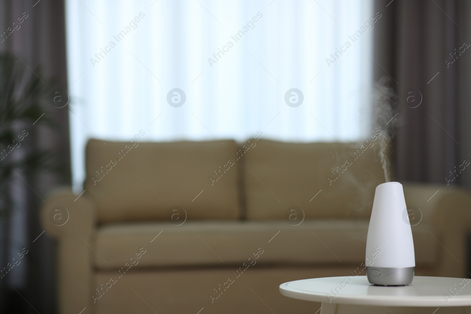 Photo of Aroma oil diffuser on table indoors. Space for text