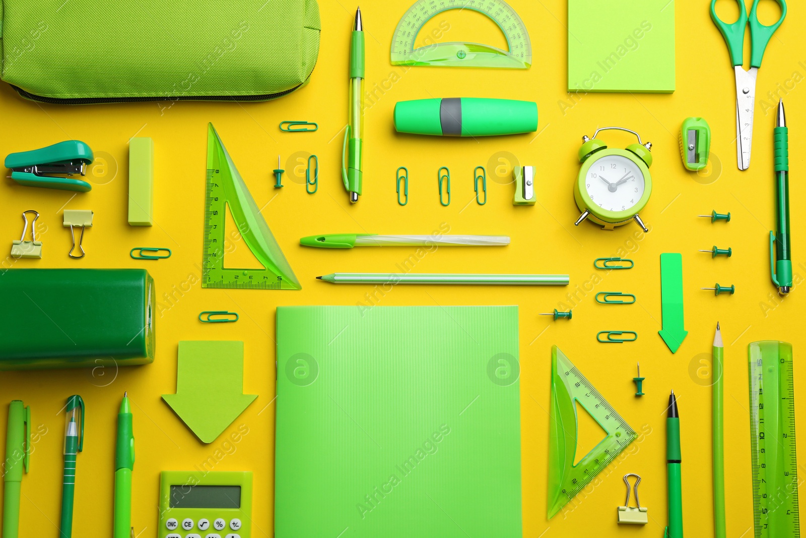 Photo of Green school stationery on yellow background, flat lay