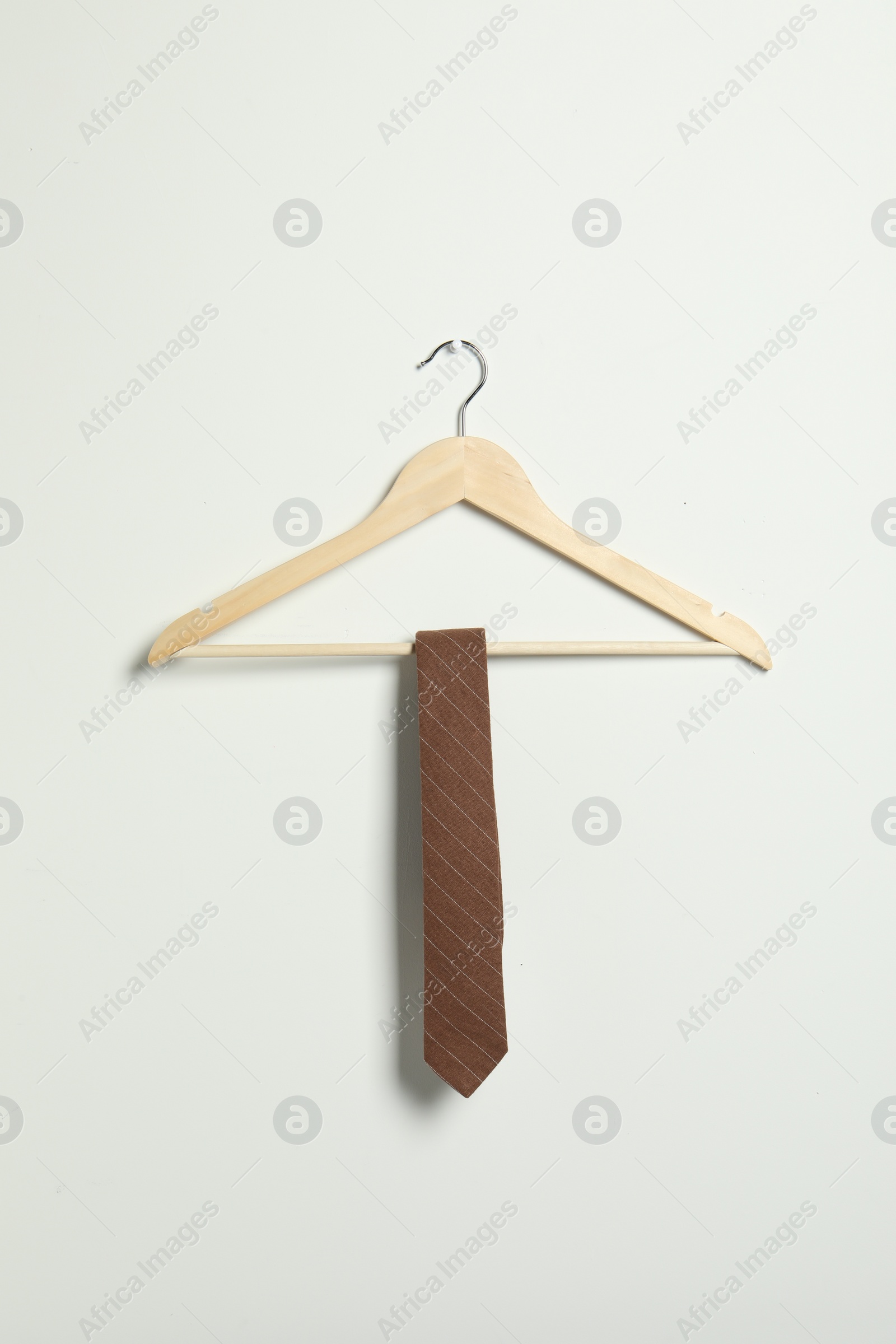 Photo of Hanger with striped necktie on white wall