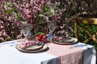 Stylish table setting with beautiful spring flowers in garden