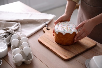 Young woman with traditional Easter cake at table in kitchen, closeup