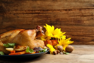 Photo of Traditional cooked turkey and autumn decor on wooden table, space for text Thanksgiving day celebration