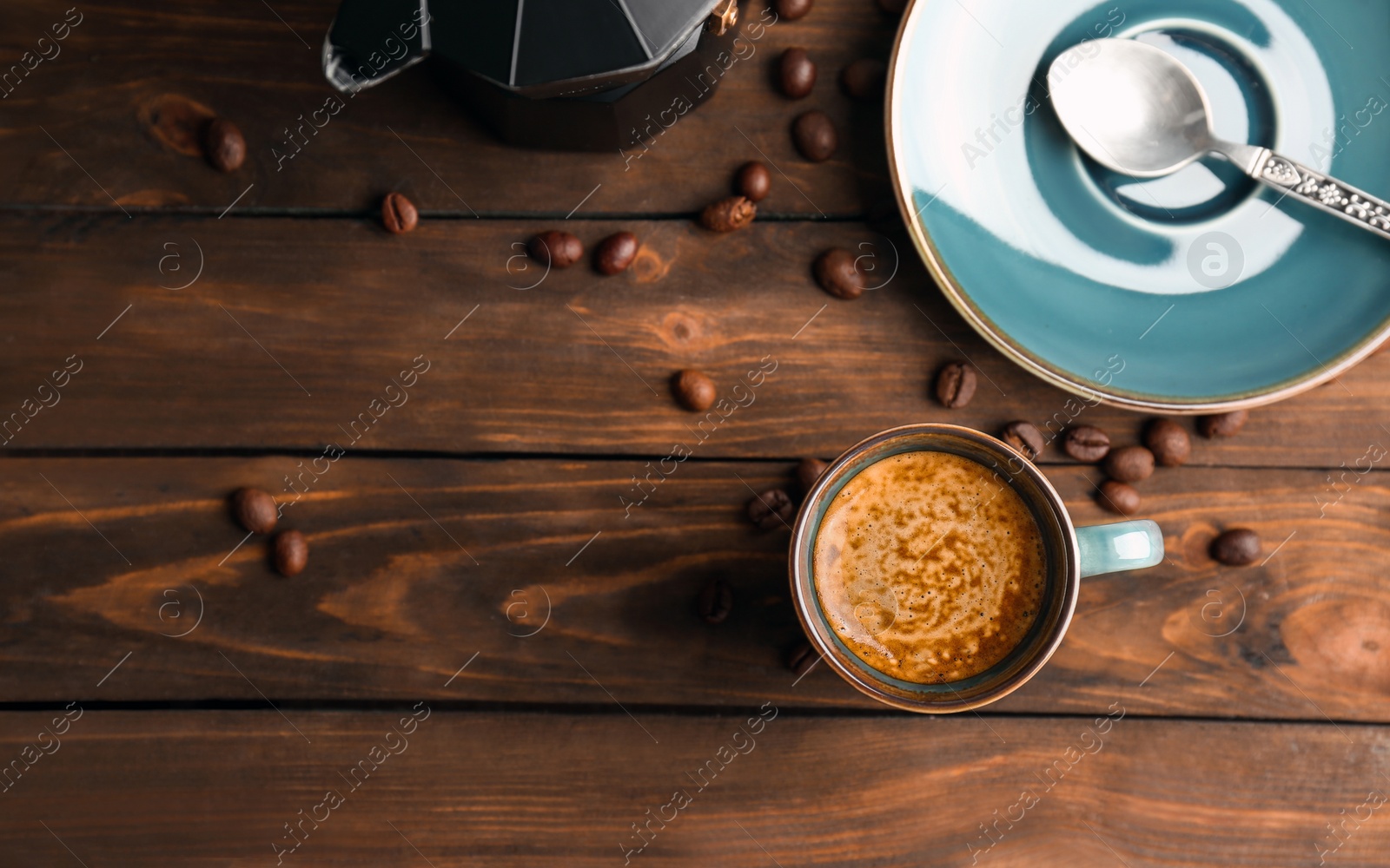 Photo of Cup of aromatic hot coffee and beans on wooden table, top view