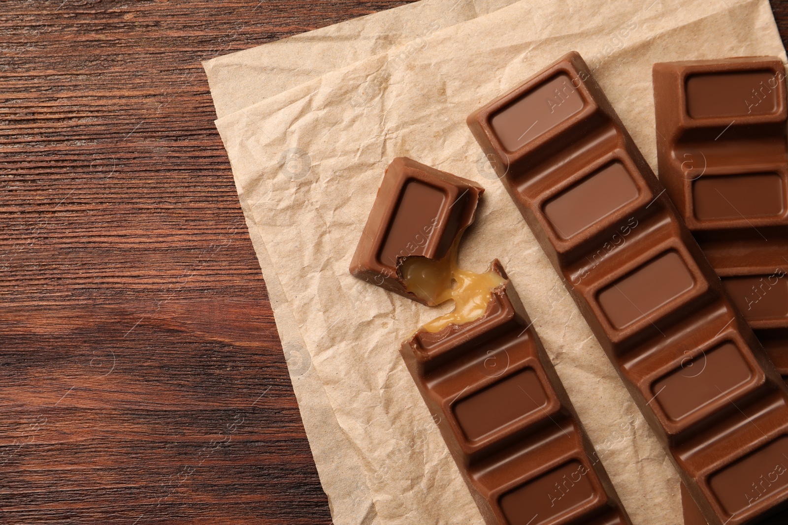 Photo of Tasty chocolate bars on wooden table, top view. Space for text