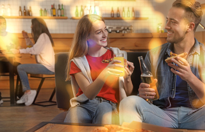 Image of Young couple eating delicious pizza in cafe, bokeh effect