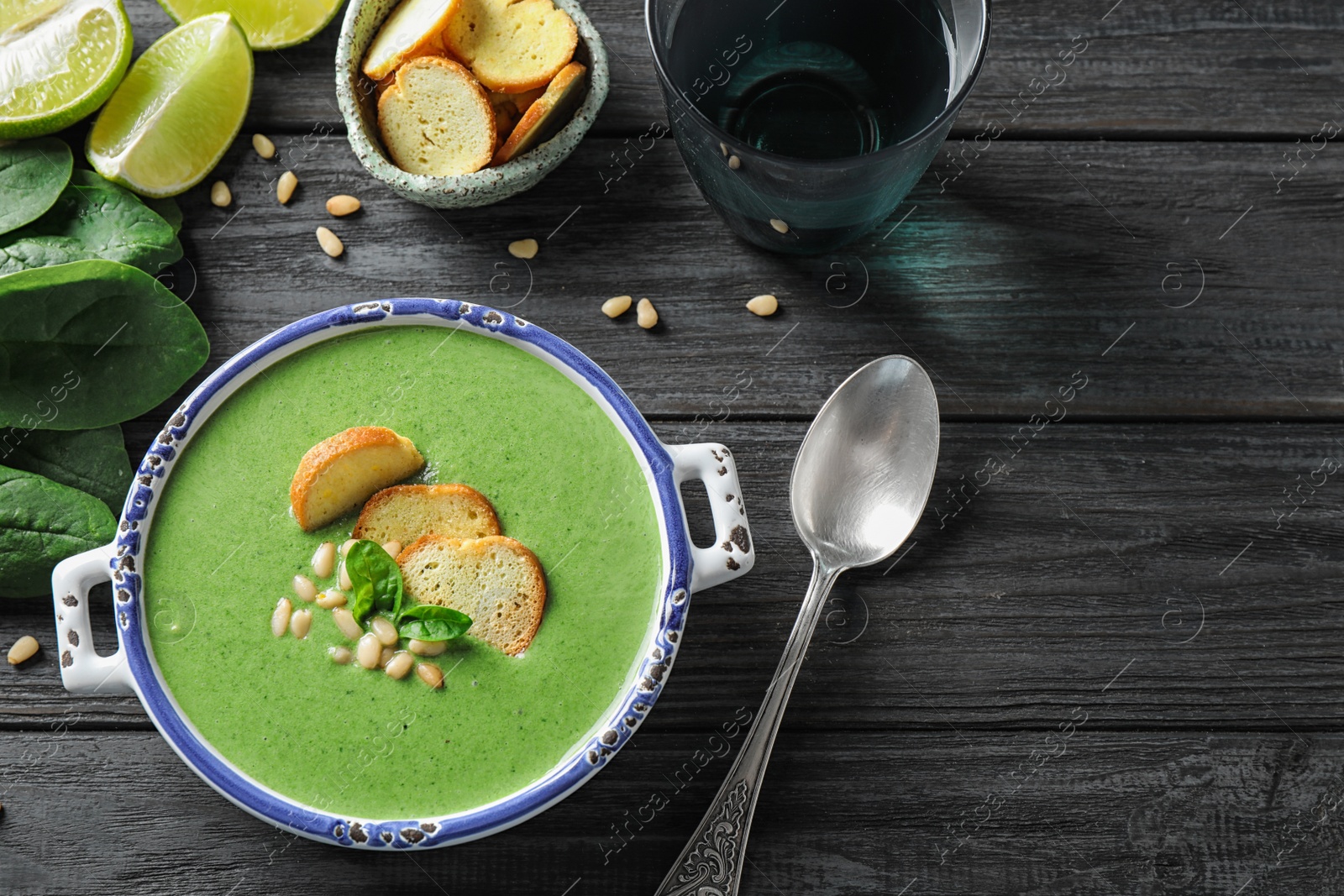 Photo of Bowl of healthy green soup with fresh spinach on grey wooden table, flat lay