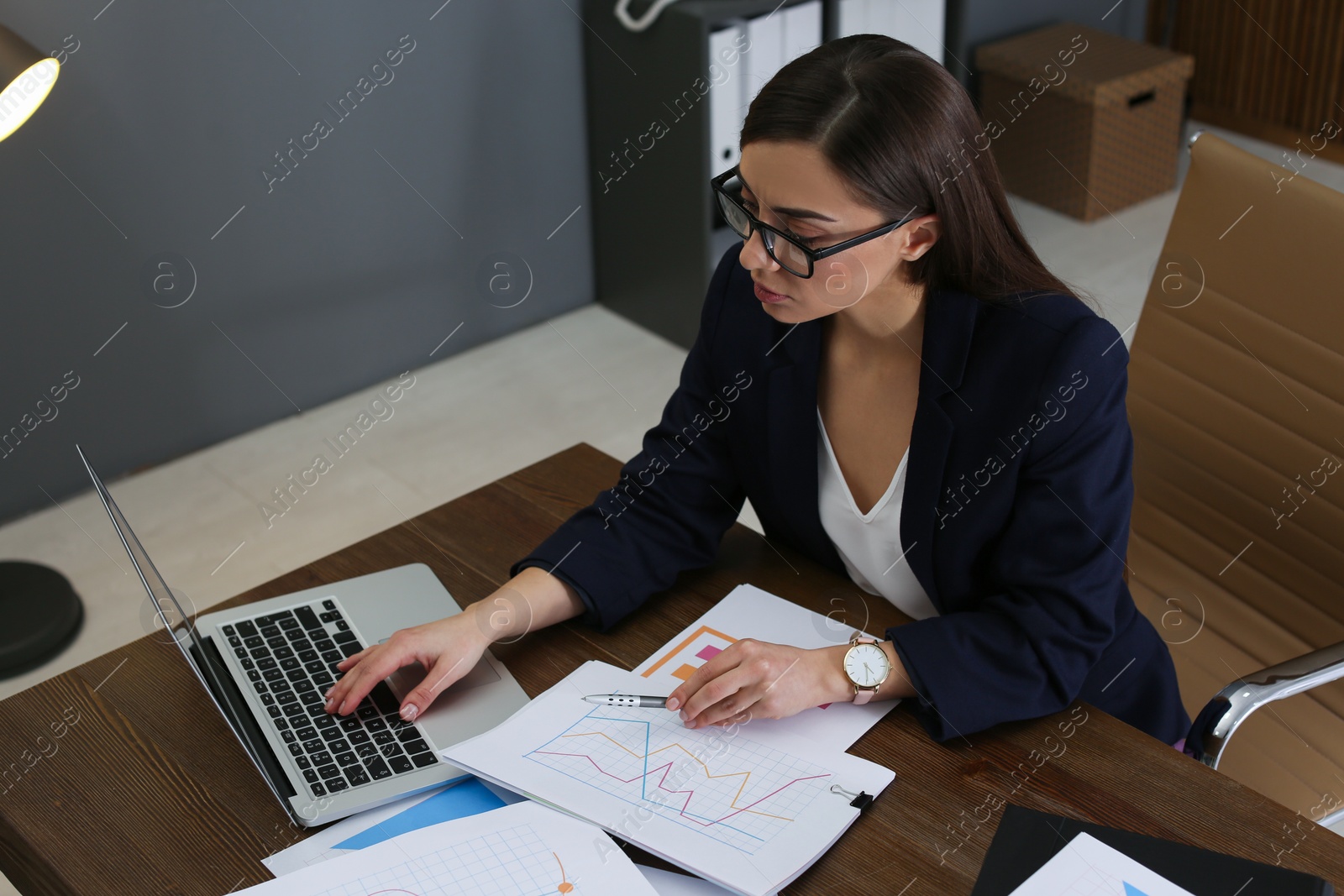 Photo of Businesswoman working with laptop and documents at table in office