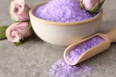 Photo of Purple sea salt and beautiful flowers on light grey table, closeup