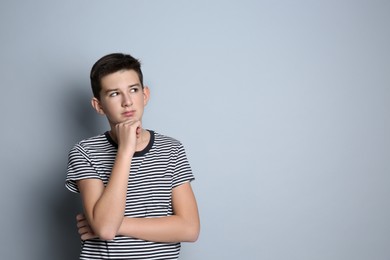 Thoughtful teenage boy on grey background. Space for text