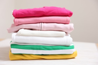 Photo of Stack of folded clothes on table against beige background