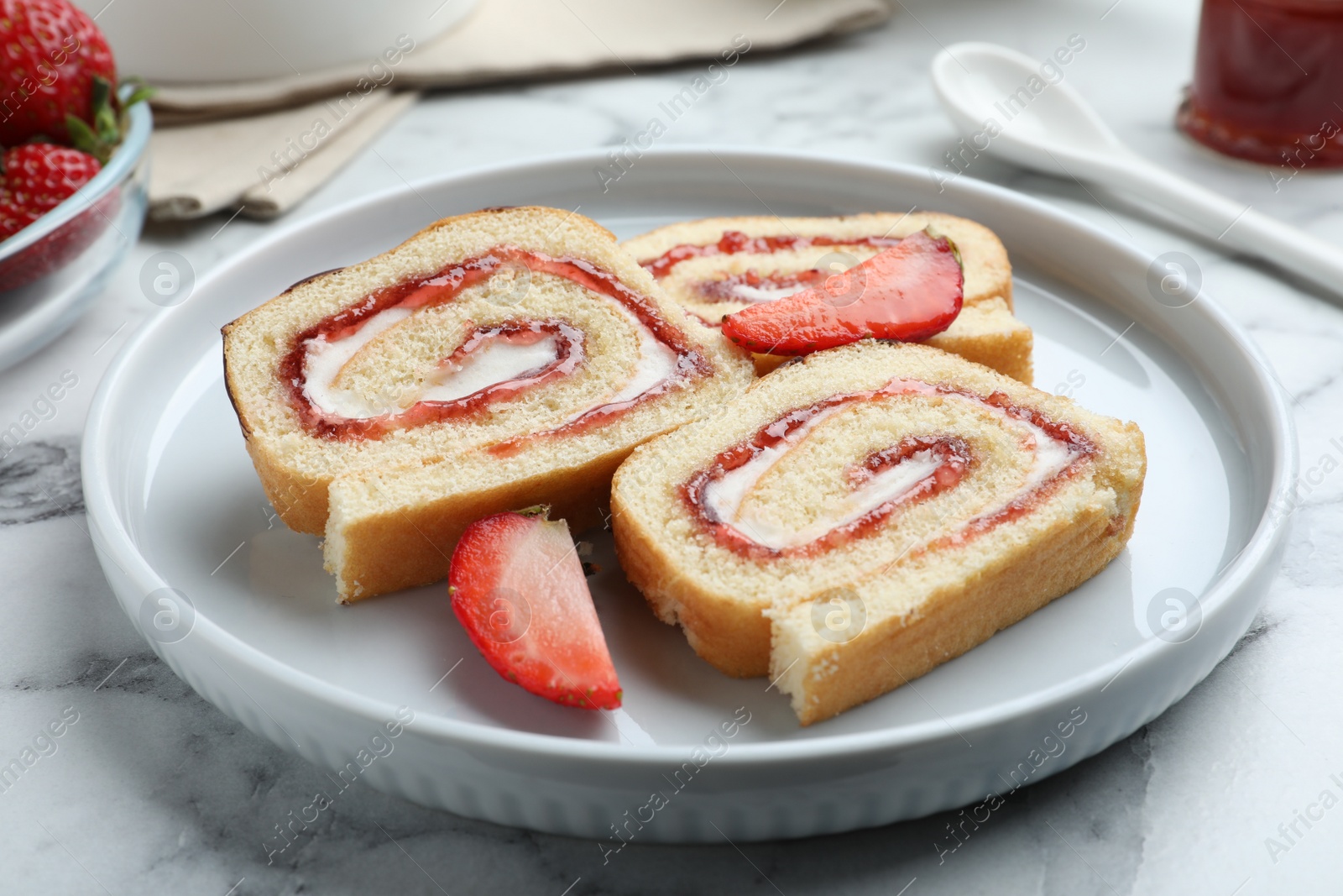 Photo of Tasty cake roll with strawberry jam and cream on white marble table, closeup