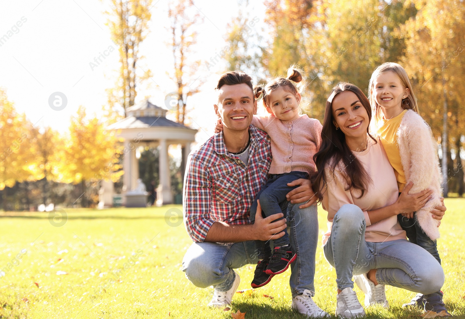 Photo of Happy family with little daughters in park. Autumn walk