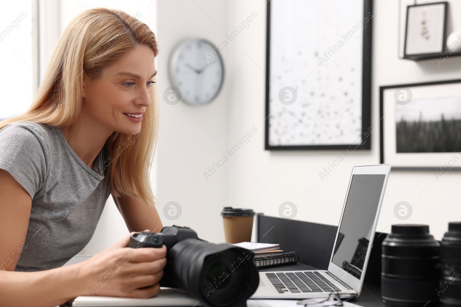 Photo of Professional photographer with digital camera at table in office