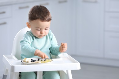 Photo of Cute little baby eating healthy food in high chair at home. Space for text