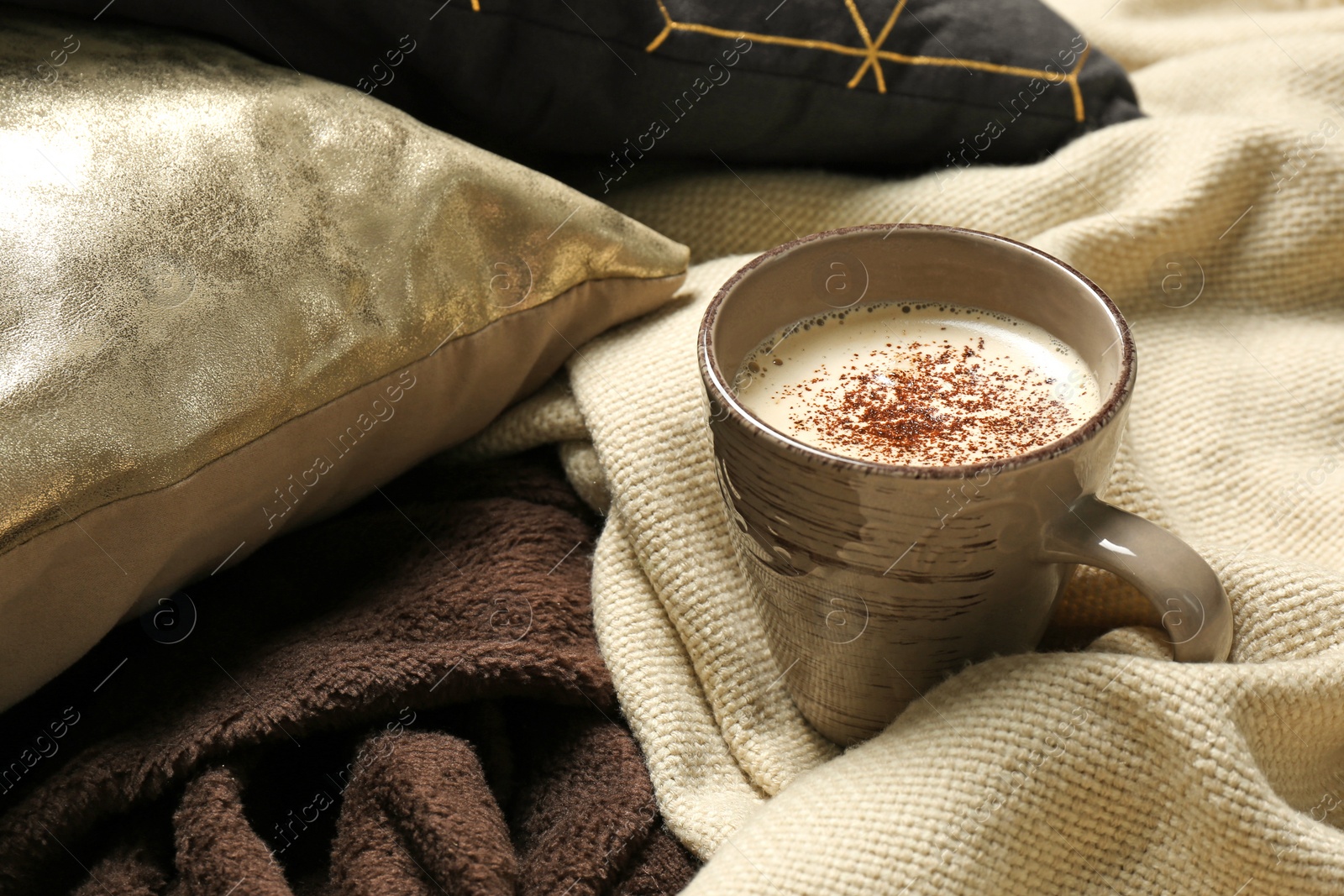 Photo of Cup of coffee, pillows and warm plaid on bed