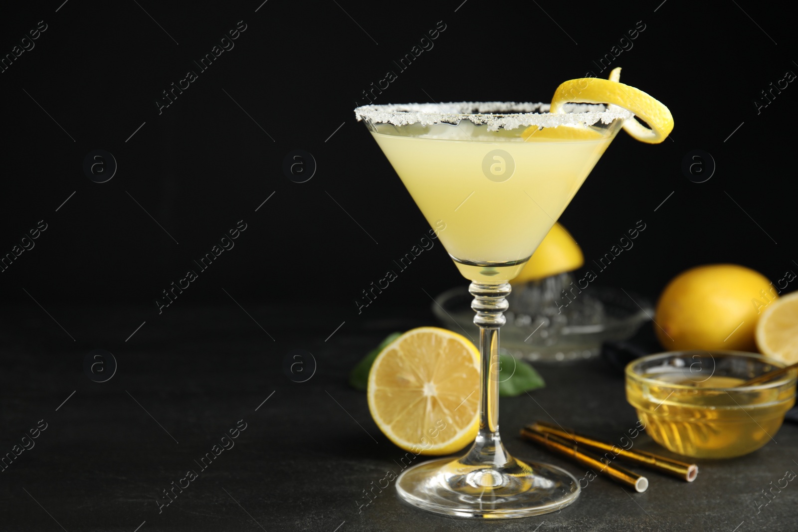 Photo of Delicious bee's knees cocktail and ingredients on black table. Space for text