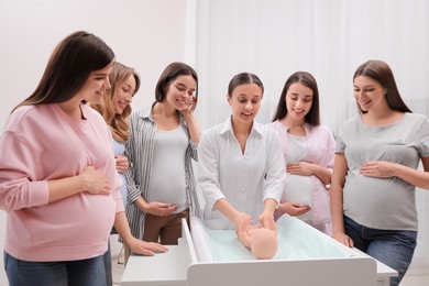 Pregnant women learning how to swaddle baby at courses for expectant mothers indoors