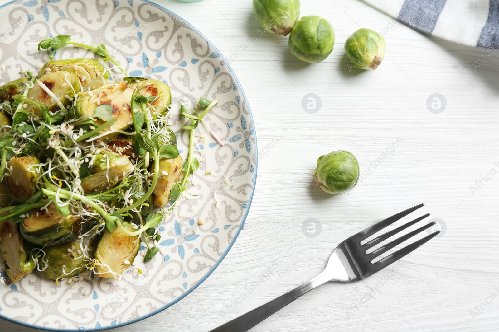 Photo of Delicious salad with roasted Brussels sprouts on white wooden table, flat lay