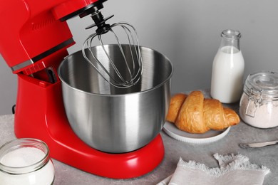 Photo of Modern red stand mixer, croissant and ingredients on gray marble table