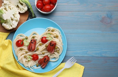 Photo of Creative serving for kids. Plate with cute octopuses made of sausages, pasta and vegetables on light blue wooden table, flat lay. Space for text