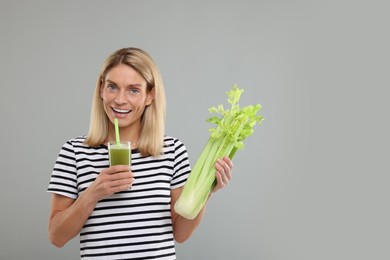 Happy woman holding glass with tasty celery juice and fresh vegetable on light grey background. Space for text