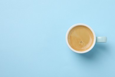 Photo of Aromatic coffee in cup on light blue background, top view. Space for text