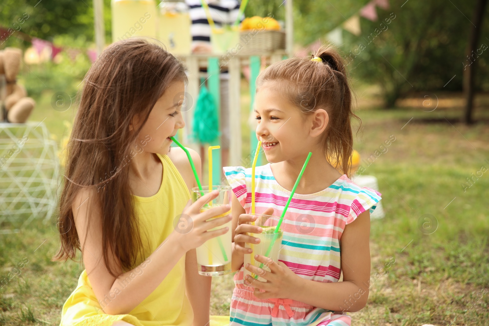 Photo of Little girls with natural lemonade in park