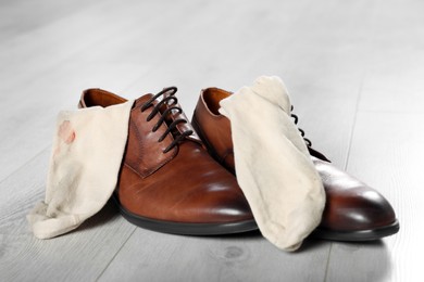 Photo of Stylish shoes with dirty socks on white wooden floor indoors, closeup