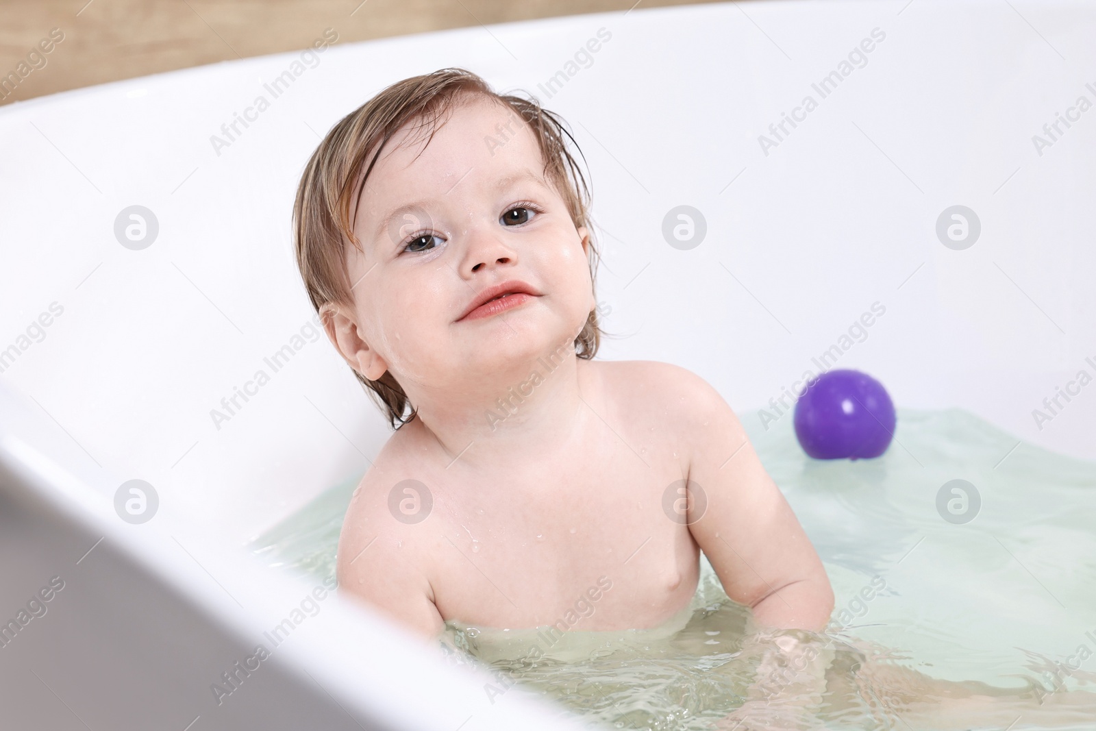 Photo of Cute little child bathing in tub at home