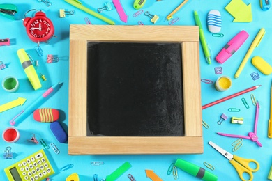 Photo of Different school stationery and blank small chalkboard on blue background, flat lay. Space for text