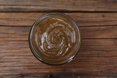 Photo of Tasty nut paste in jar on wooden table, top view