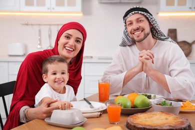 Happy Muslim family eating together at table in kitchen