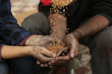 Poor homeless people taking wheat from donator outdoors, closeup