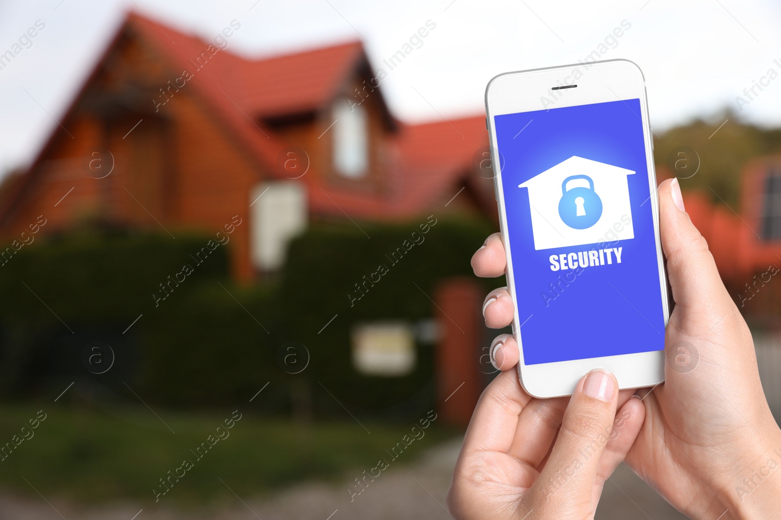 Image of Home security system. Woman with smartphone near her house outdoors, closeup