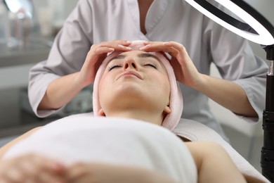 Photo of Cosmetologist making face massage to client in clinic, closeup