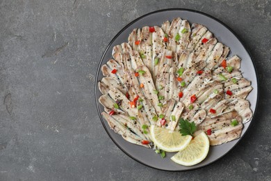 Photo of Tasty pickled anchovies with spices on grey textured table, top view. Space for text