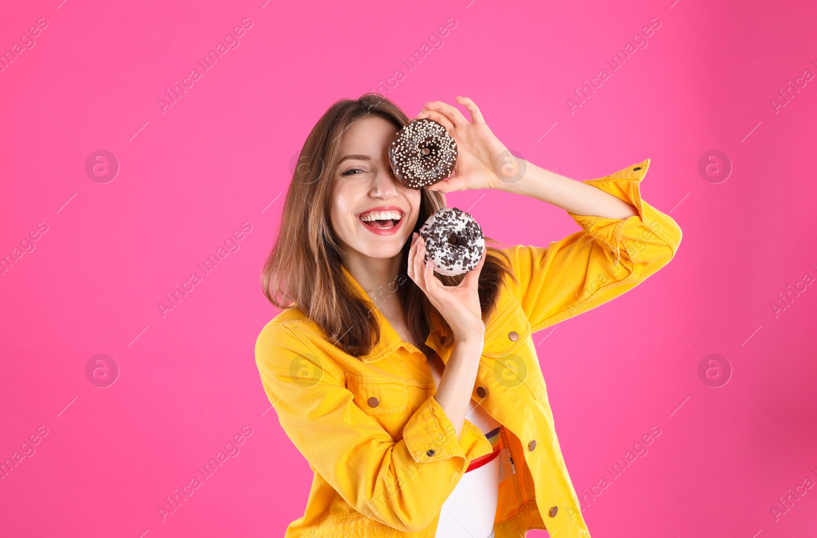 Photo of Beautiful young woman with donuts on pink background