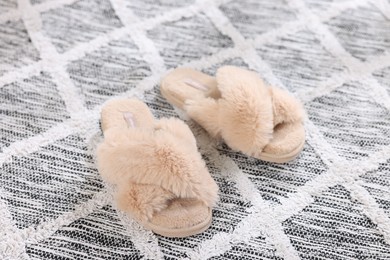 Beige soft slippers on beautiful carpet, closeup