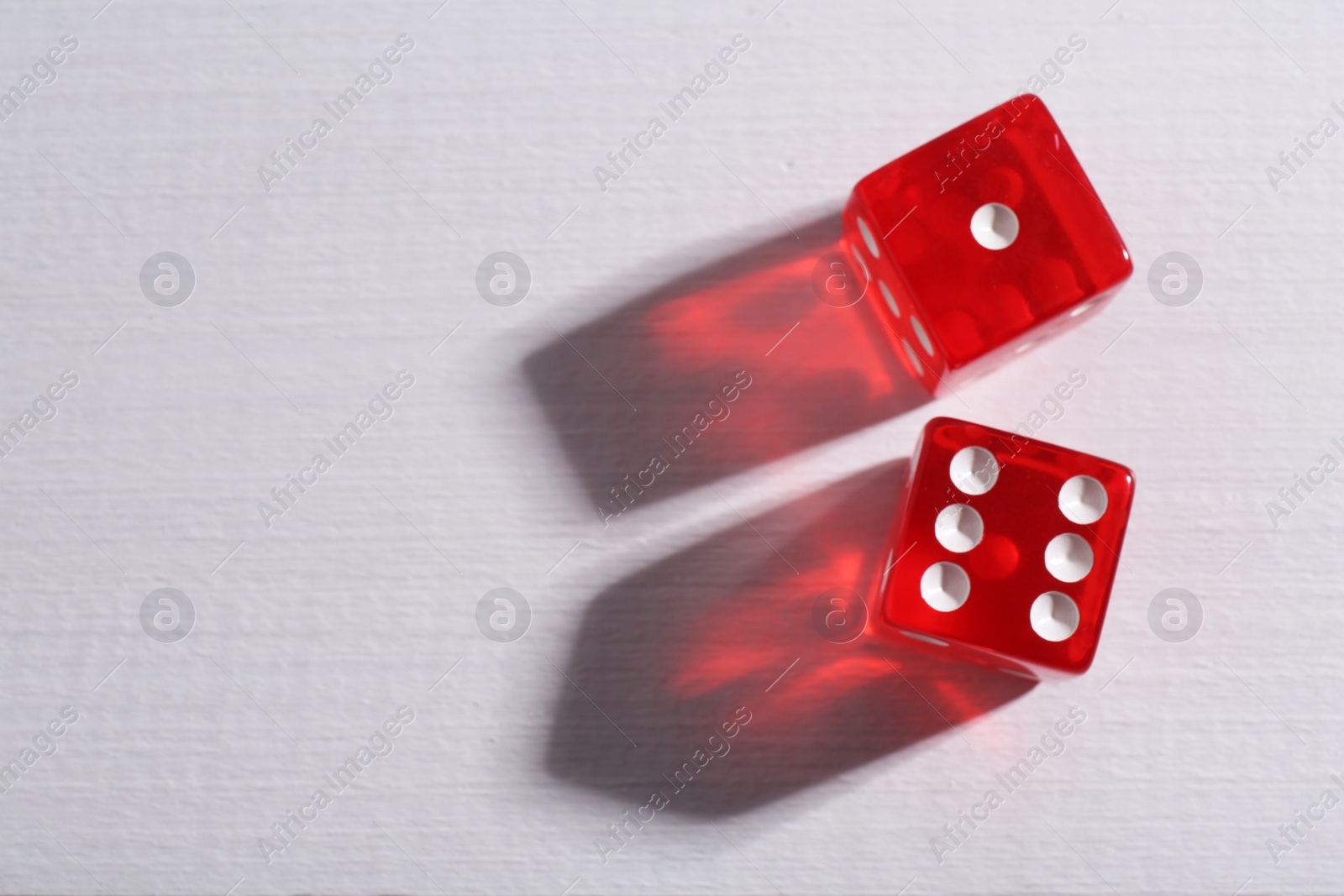 Photo of Two red game dices on white wooden table, flat lay. Space for text