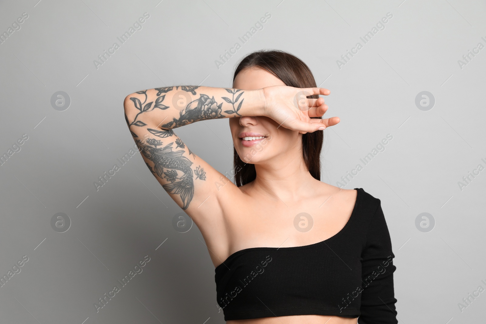 Photo of Beautiful woman with tattoos on arm against grey background