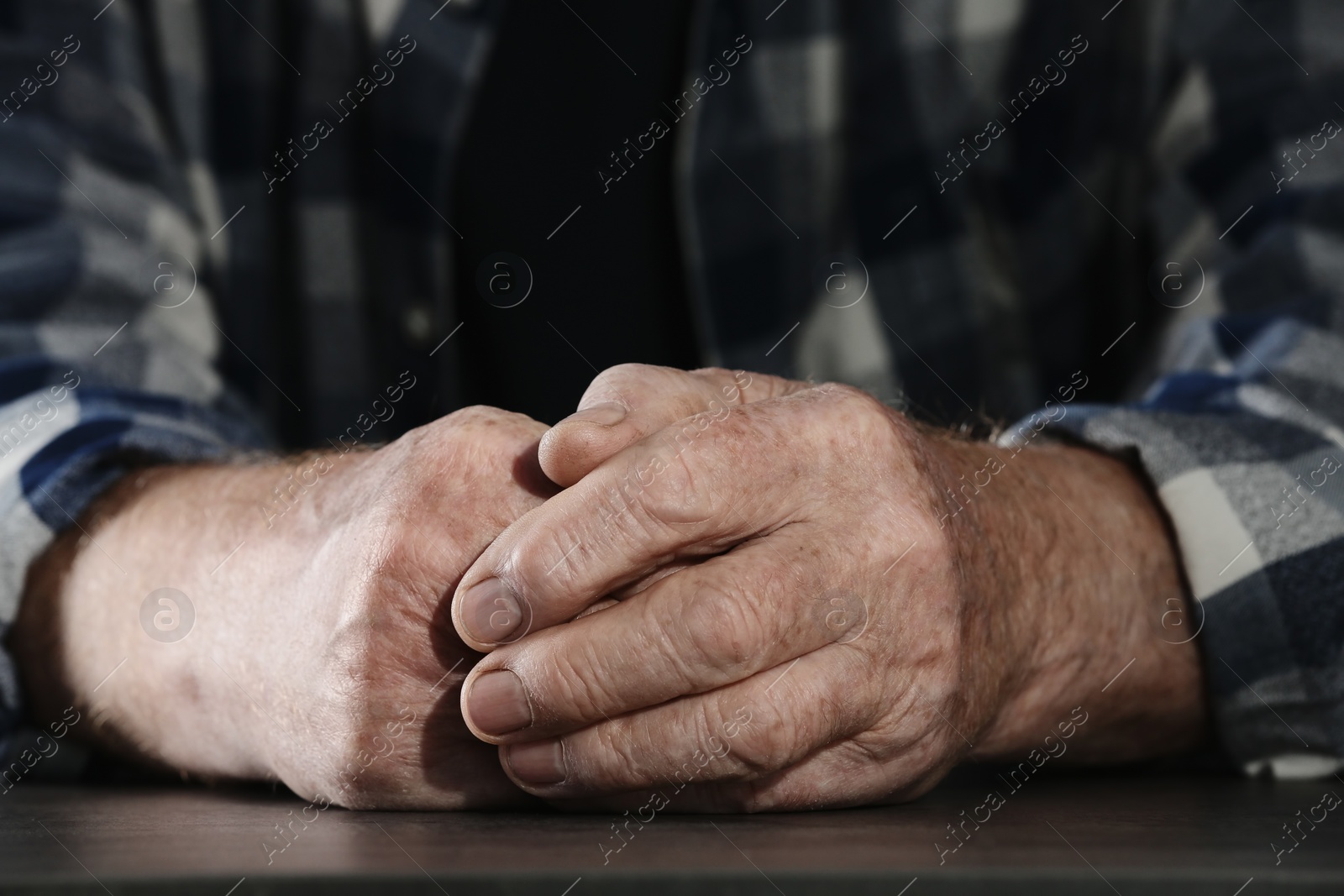 Photo of Poor elderly man sitting at table, focus on hands