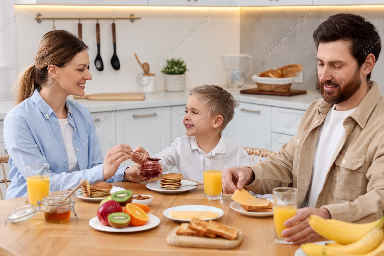 Photo of Happy family having breakfast at table in kitchen